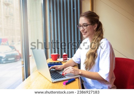 Happy smiling woman skilled content writer for business presentation remote working on laptop computer while sitting in coffee shop near window with copy space 