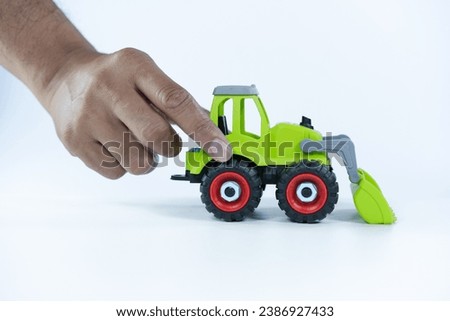  hand man playing with the car close on a white background. Plastic child toy on white backdrop. Construction vehicle. Children's toy. Tractor Toy.