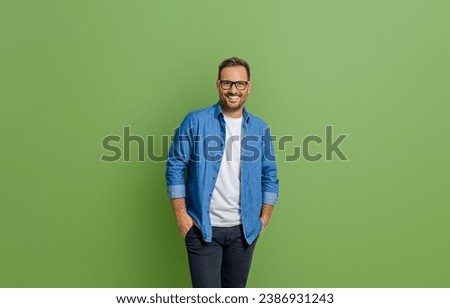 Portrait of young businessman with hands in pockets standing isolated against green background