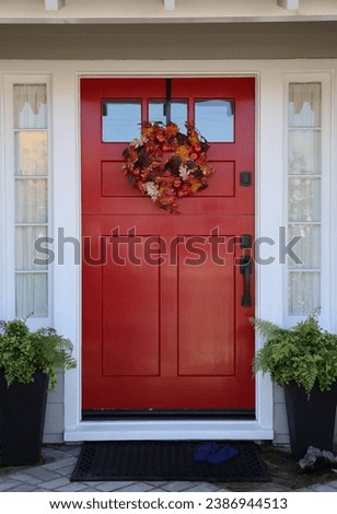 Bright red Dutch door with autumn leaves wreath