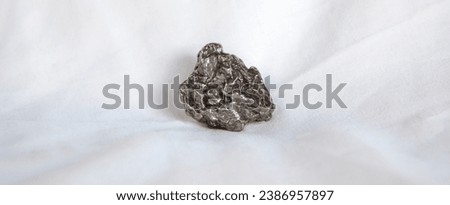 Nickel-iron type meteorite fragment. Isolated over white background. Placed over cotton cloth