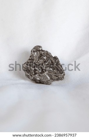 Nickel-iron type meteorite fragment. Placed over cotton cloth