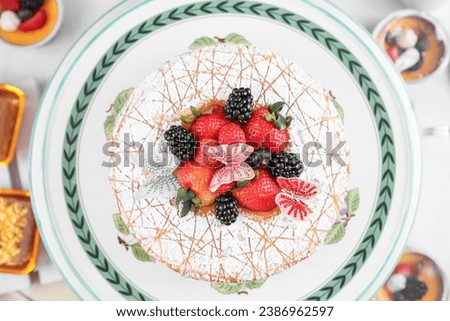 Cake with whipped blue and pink cream, fresh strawberries, blueberries and blackberry. Top view. Picture for a menu or a confectionery catalog.