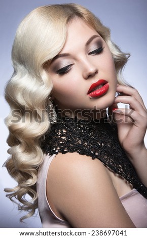 Beautiful blonde in a Hollywood manner with curls, red lips and lace dress. Beauty face. Picture taken in the studio on a white background.