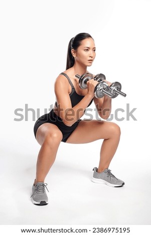 an asian woman is working out with dumbbells wearing the sport exercise suit with white background, Royalty-Free Stock Photo #2386975195