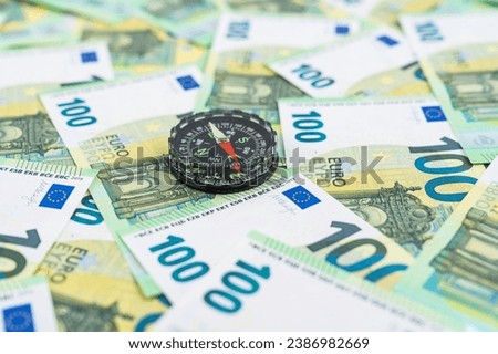  Compass over euro banknotes, 100 euro money bills, money movement concept. High quality photo