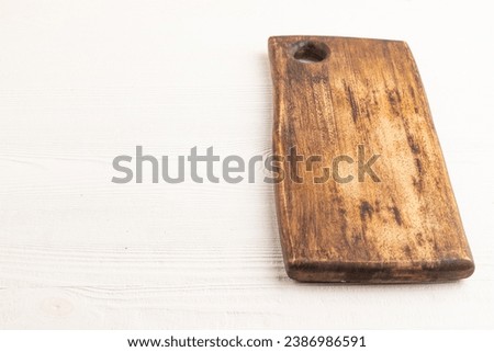 Empty rectangular wooden cutting board on white wooden background. Side view, copy space.