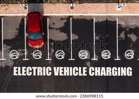 Aerial view directly above an electric vehicle charging station with parking spaces and road markings denoting charging bays