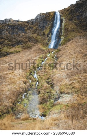 The waterfall is flowing down from the mountain