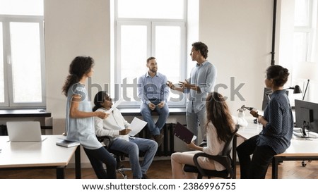 Diverse young business team employee speaking to group of colleagues, sharing ideas on office meeting, talking to group. Corporate teacher, mentor training multiethnic staff. Banner shot