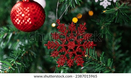 Amidst the evergreen branches, a red Xmas snowflake decoration adorns the tree with festive Christmas balls, creating a beautiful and celebratory atmosphere
