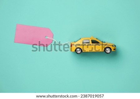Toy taxi car model with sale tag on blue background. Top view