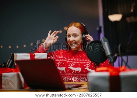 A girl blogger is doing a Christmas giveaway on her channel. Portrait of a girl in a Christmas sweater with gifts in her hands in a home studio.