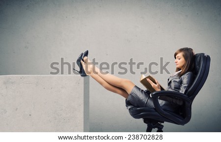 Young attractive businesswoman reading book in chair