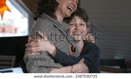 Candid mother and pre-teen boy laughing together. Authentic moment of family lifestyle joy with child with arm around mom in affectionate embrace Royalty-Free Stock Photo #2387030735