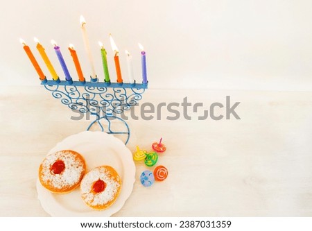 Hanukkiah Menorah of Hanukkah with eight lit colored candles and one additional candle. With donuts and spinning tops svivon, white background, with free space for text. for Hanukkah, a Jewish holiday