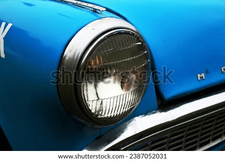 Photo of the front headlight of a blue old car. Transport. Retro. Vintage.