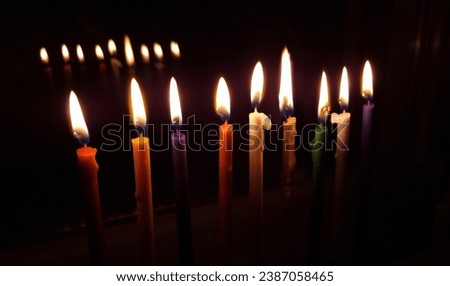 Hanukkah Menorah with lit colored candles, intended for Hanukkah, a Jewish holiday, the traditional festival of lights. On the window with reflection.
on a dark background 
