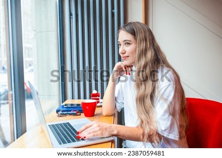 Dreaming female professional web counter writer looking in window during remote work on laptop computer while sitting in coffee-house 