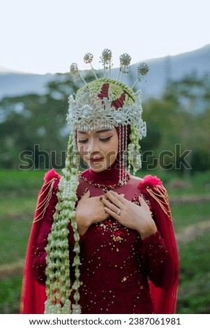 The female model is wearing make-up, wearing a property called SIGER SUNDA and red traditional Indonesian wedding clothes. Portrait of a traditional Javanese bride. Indonesian bride. Red wedding dress