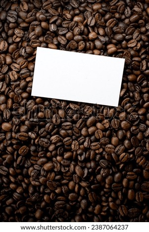 Freshly roasted coffee beans background with business card above, top view. coffee shop. Coffee beans background. Background of roasted coffee beans