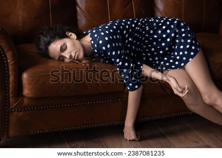 Exhausted woman lying on couch, sleeping after long workday, falling asleep, tired young female with closed eyes resting on sofa, taking nap, daydreaming, fatigue and lack of energy concept Royalty-Free Stock Photo #2387081235
