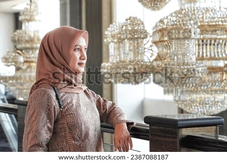 A beautiful woman in a hijab wearing a traditional Indonesian kebaya dress with a blur interior background. Beautiful woman model in hijab.