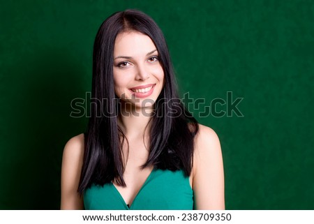 Woman smiling on green background.Young brunette girl portrait.Happy female. Surprised smiling attractive caucasian gir and a lot of copyspace. Natural looking cute person. Anadorned beauty,no make-up