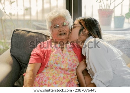 Grandmother receives a kiss from her loving granddaughter. Royalty-Free Stock Photo #2387096443