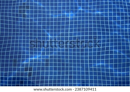 Top view photo of a detail of a empty swimming pool deep down tiled floor with the water creating a distortion with the lights relfections as the water moves due to the swimmers