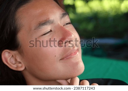 Close-up Portrait head shot photo of a young handsome good looking eurasian caucasian chinese male boy with long hair dresses in a ponytail pony  hairstyle with smiling amuzed happy neutral expression
