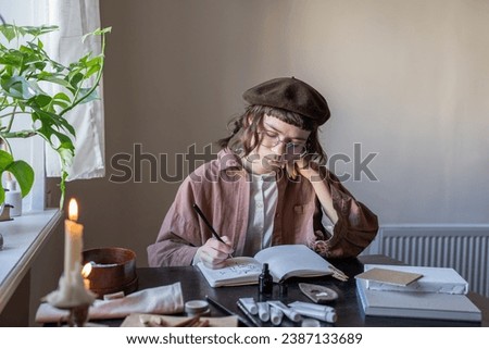 Animated cartoon artist sketching with ink in cozy studio. Serious tired girl in glasses, vintage clothes, beret creating animation. Hobby, creative pastime, freelance work, professional occupation