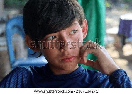 Head shot portrait photo of a good looking handsomeoung teeanger kid male boy looking a aside with his hand touching his cheek in a outsdoor outside setting location