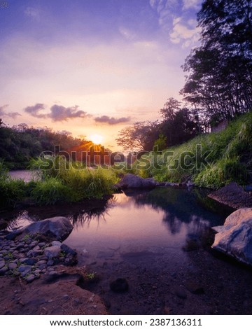The spring reflects the light of the evening sun. The water is clear and there are rocks in it