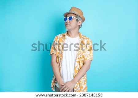 Portrait of Asian energetic senior man posing on blue background with travel clothes. mature man, Asian man. Elderly, Holiday, Travel. studio shot. Multiple emotions.