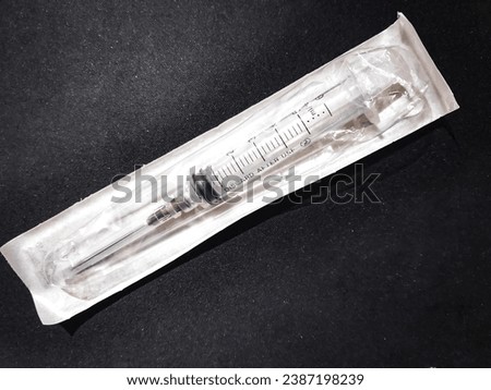 a syringe still wrapped in plastic on a black background.