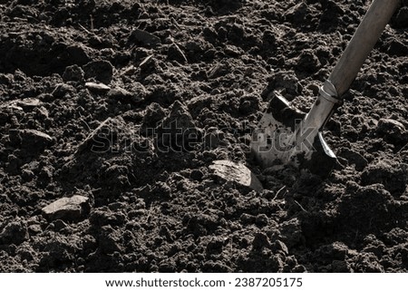 Tilled soil on a homestead plot. A shovel stuck in the ground Royalty-Free Stock Photo #2387205175