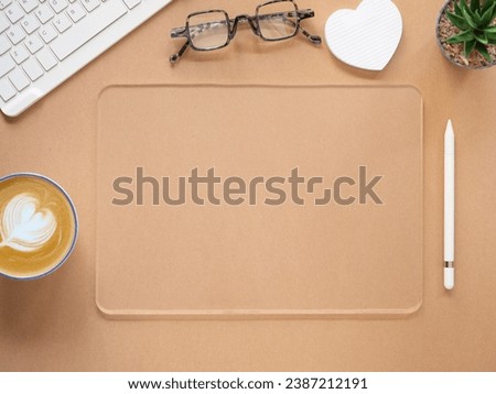 Top view, flat lay template, mock-up transparent tablet computer amd wireless pen, keyboard, cactus, coffee cup on brown workplace. Business, technology concept.
