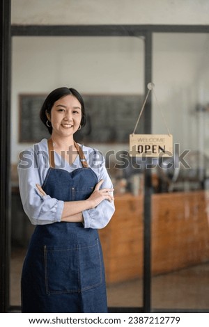 Vertical image of startup business owner standing in an apron. SME entrepreneur invite and present with pride of her coffee shop business.
