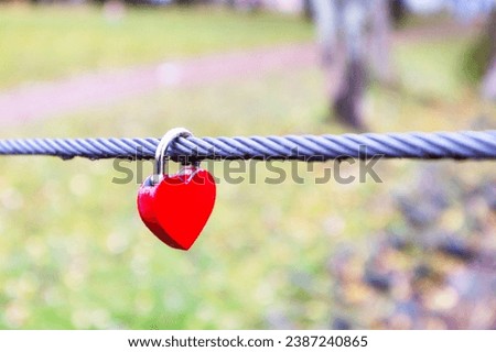 
A red latch on a metal rope in the shape of a heart