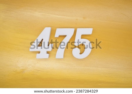 The golden yellow painted wood panel for the background, number 475, is made from white painted wood. Royalty-Free Stock Photo #2387284329