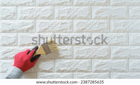 A man repairing the outer wall.Painting a white brick wall. Royalty-Free Stock Photo #2387285635