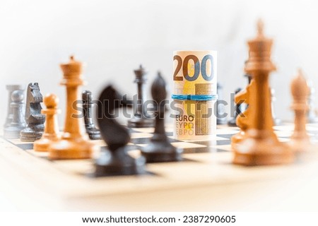 Chess game with blurred chess pieces on board with rolled 200 euro bills with blue rubber bann. High quality photo