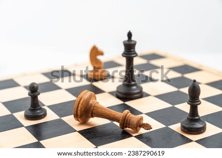 Chess game with black and white pieces on the chessboard. White king defeated, black pawn, bishop and king standing. High quality photo