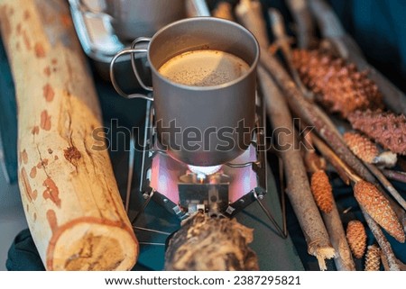 Outdoor kitchen equipment camp fire and brewing tea pot moka coffee drip cup,with wooden table camping gas stove set in nature outdoor,mountain background,concept camp and travel Royalty-Free Stock Photo #2387295821