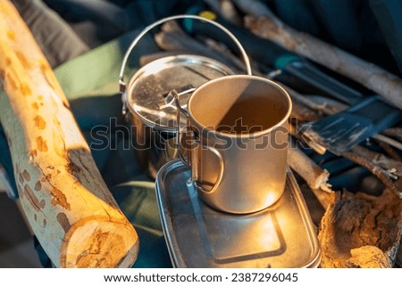 Outdoor kitchen equipment camp fire and brewing tea pot moka coffee drip cup,with wooden table camping gas stove set in nature outdoor,mountain background,concept camp and travel Royalty-Free Stock Photo #2387296045
