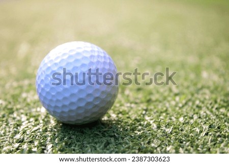 A picture of a white golf ball placed on artificial grass in the center of the picture.
