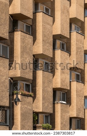 Modern architecture in the style of brutalism. Fragment of a concrete building with windows and balconies in Warsaw, Poland. New Brutalism is a branch of postwar architectural modernism.  Royalty-Free Stock Photo #2387303817