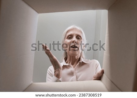 Close up inside of cardboard package bottom view, mature woman open parcel box looks at broken items feels frustrated. Complaints, refund, negative experience buying on internet, bad delivery services Royalty-Free Stock Photo #2387308519