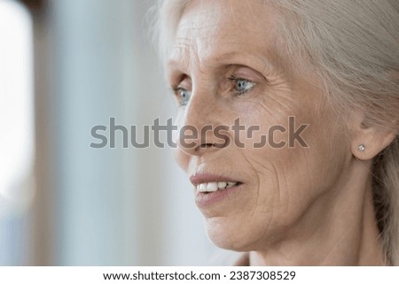 Close up face view of pensive elderly retired woman staring into distance, looks thoughtful, deep in thoughts, recollect memories, having nostalgic mood, remembering past. Older gen female portrait